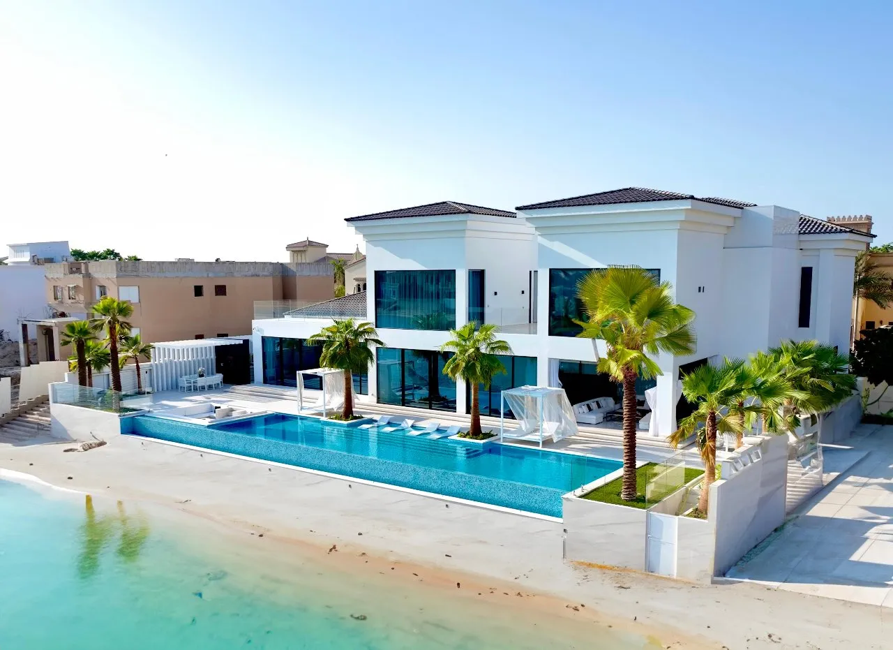 A beautiful white house with a pool and palm trees, offering a serene and luxurious living space.