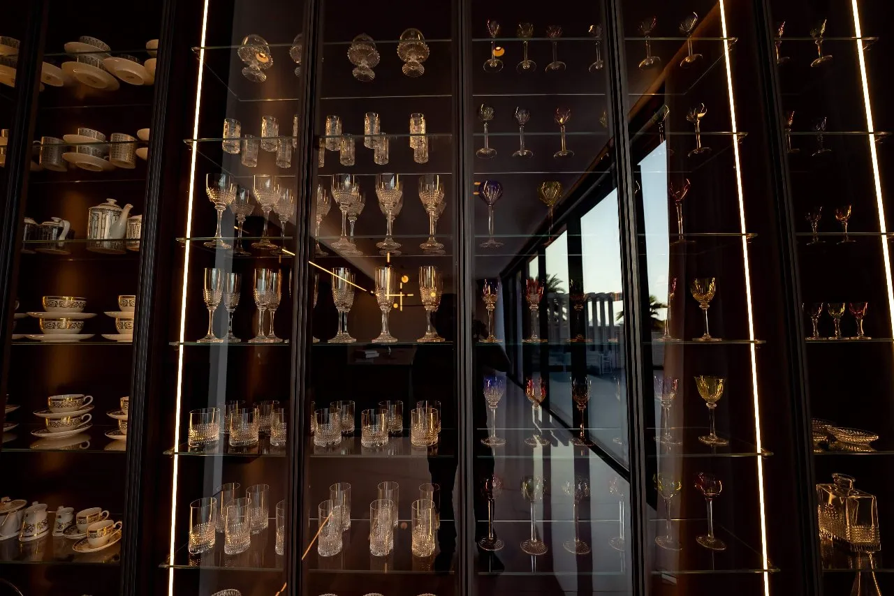 A display of various glasses and dishes in a glass case. Perfect for showcasing a wide range of tableware.