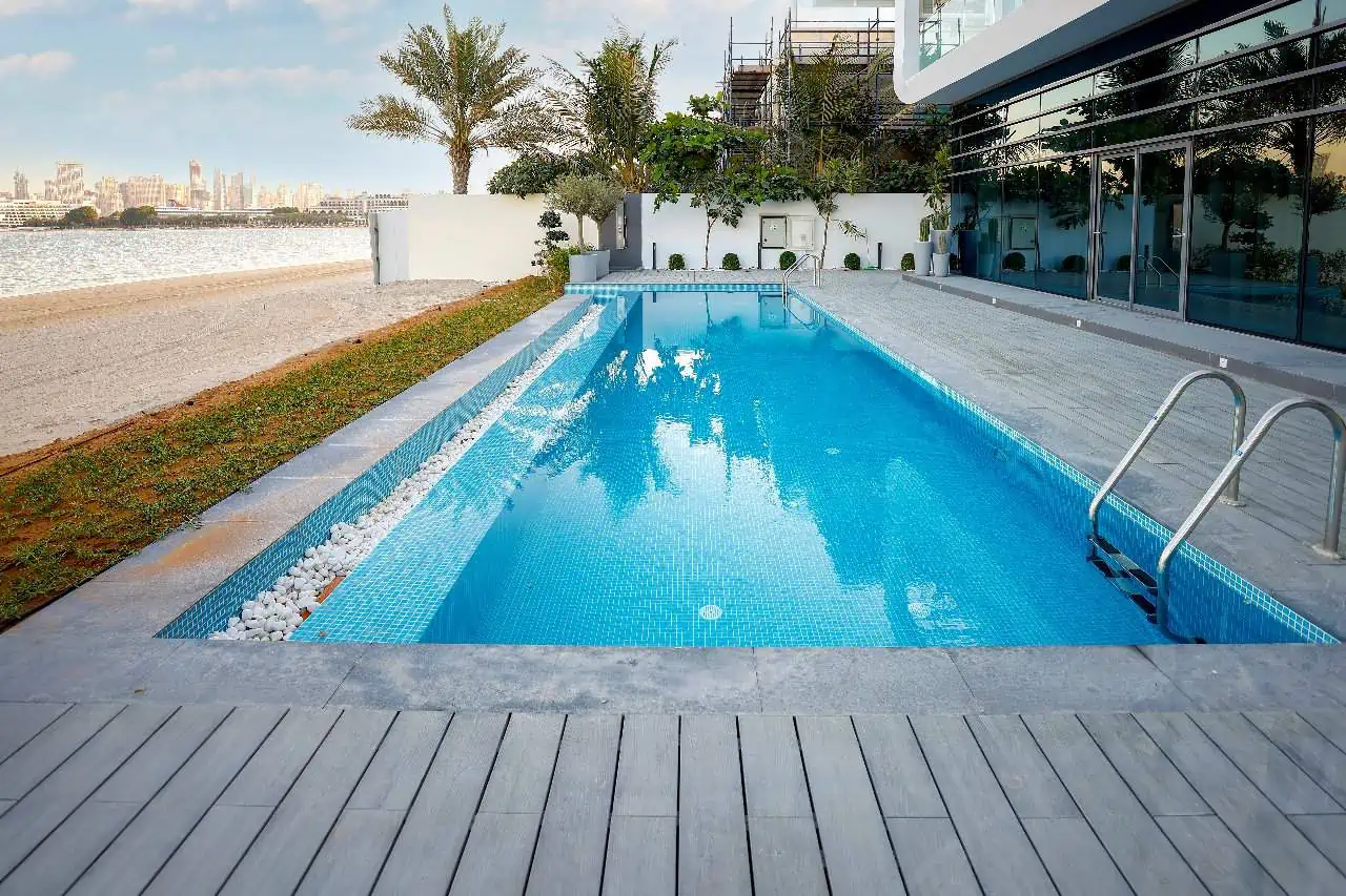 A serene swimming pool nestled in front of a beautiful building, inviting you to relax and unwind.