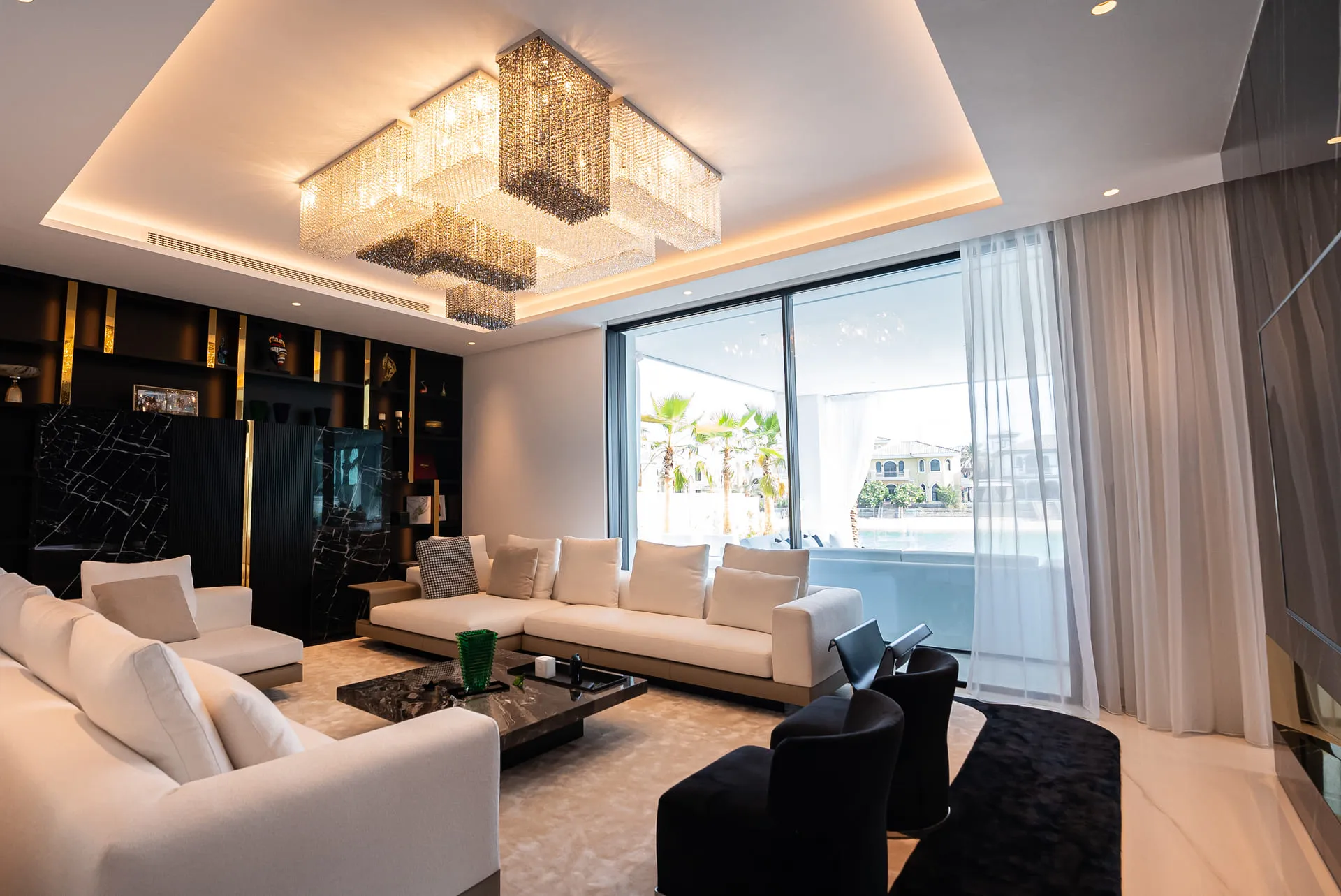 A modern living room with white furniture and a chandelier, creating an elegant and stylish ambiance.
