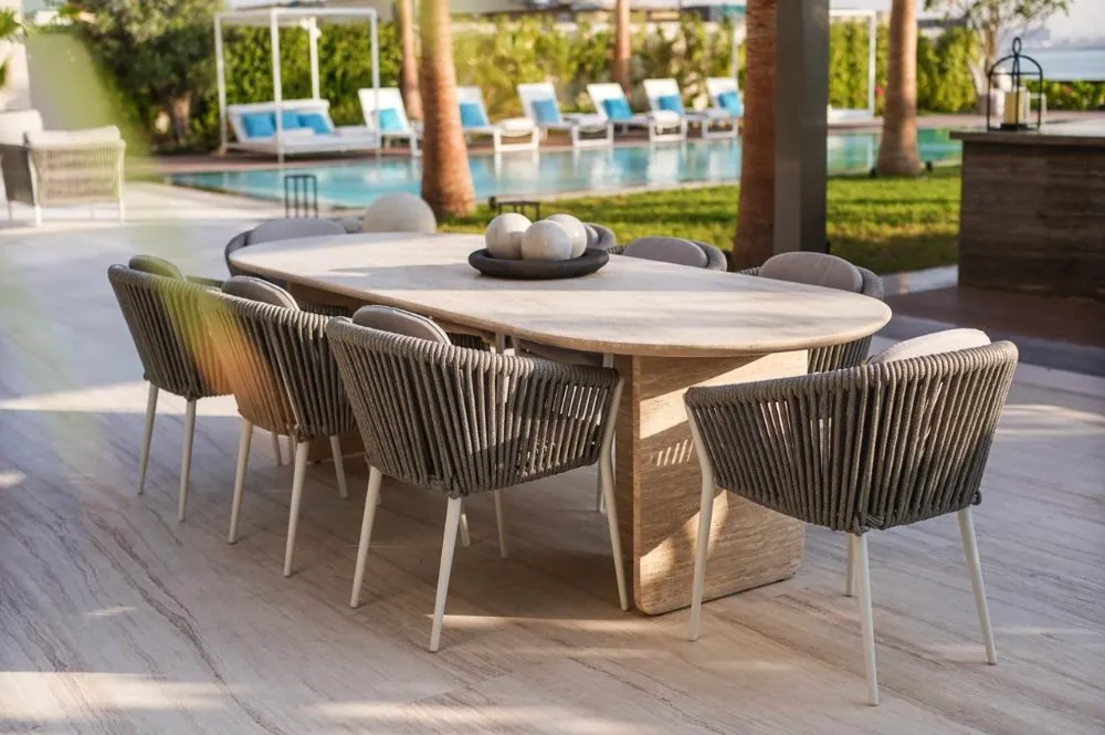 A stylish outdoor dining table with chairs beside a sparkling pool, perfect for gatherings and enjoying sunny days.