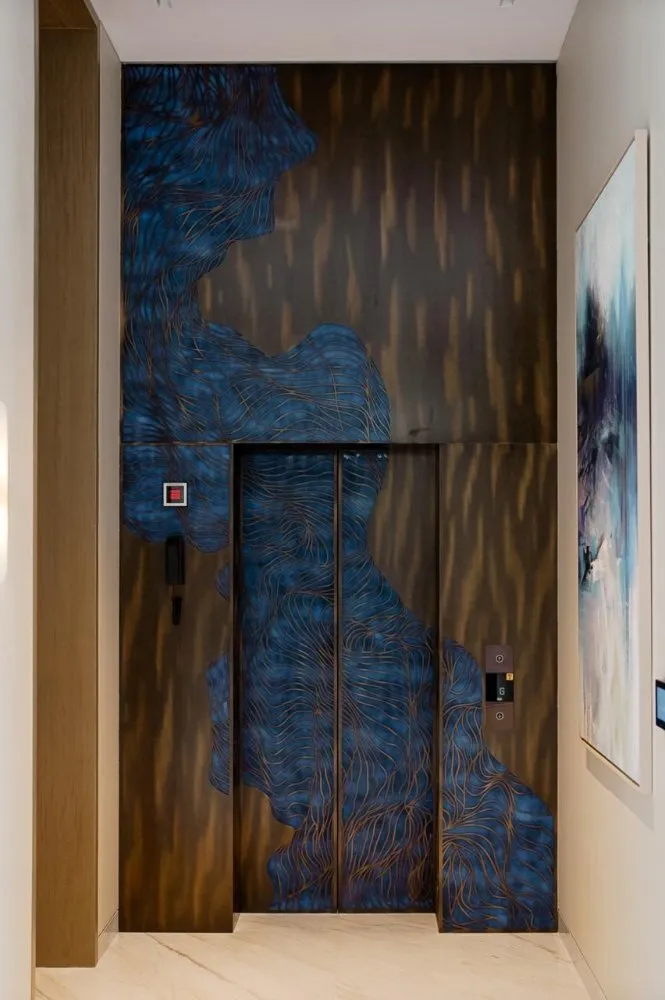 Elevator with sleek blue and gold abstract wall art, set in a modern hallway, alongside a contemporary painting.
