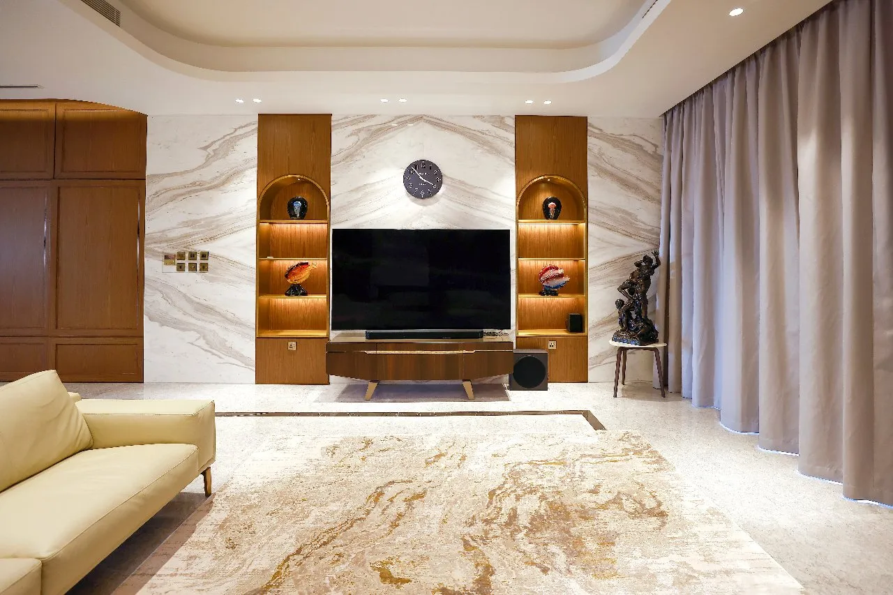 A cozy living room with a big TV and elegant marble walls, perfect for relaxing and enjoying entertainment.