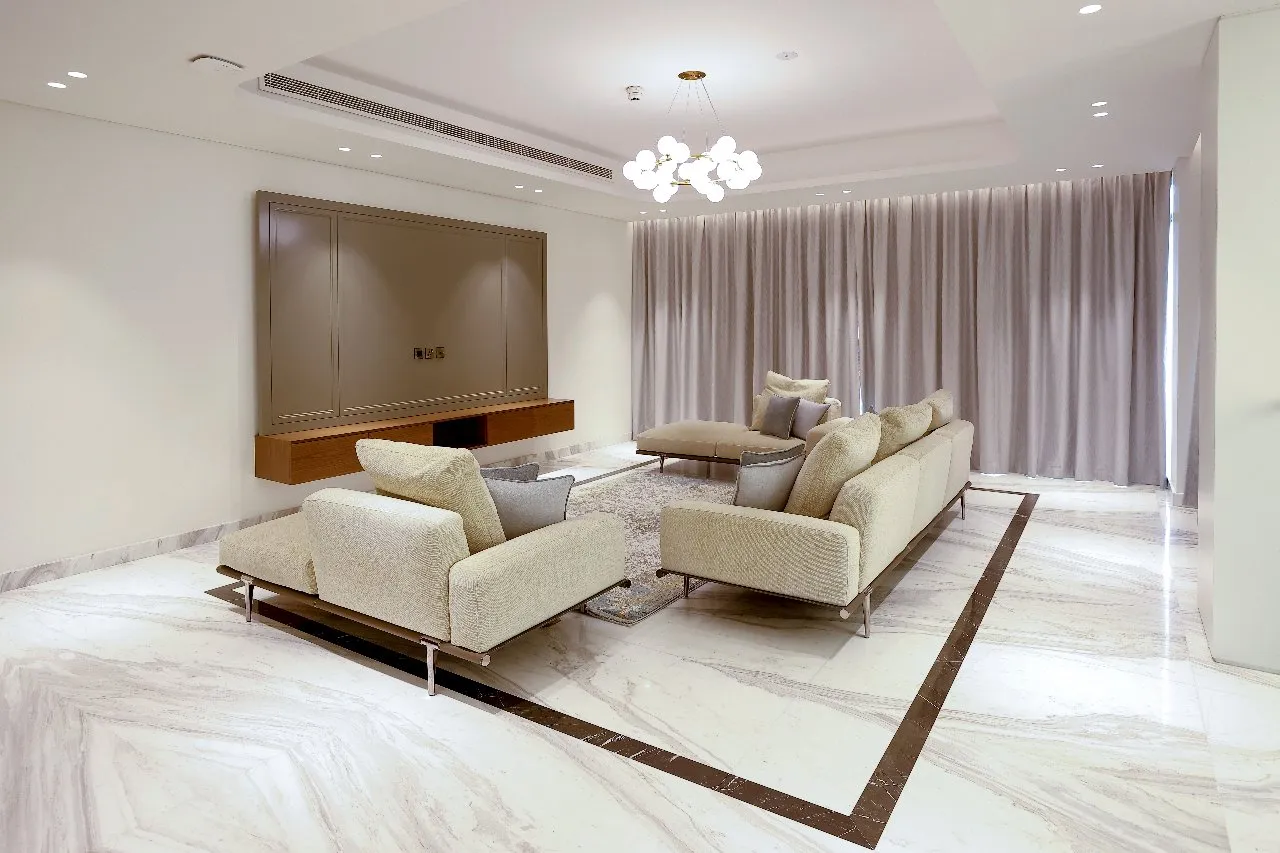 A modern living room with sleek marble flooring and elegant white furniture.