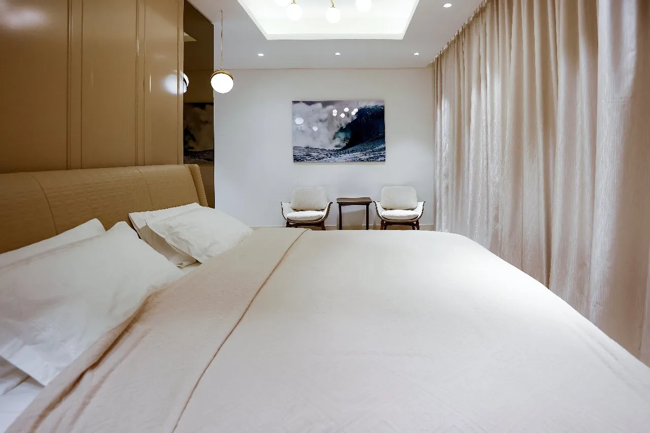 A serene bedroom adorned with a large bed and a captivating artwork on the wall.